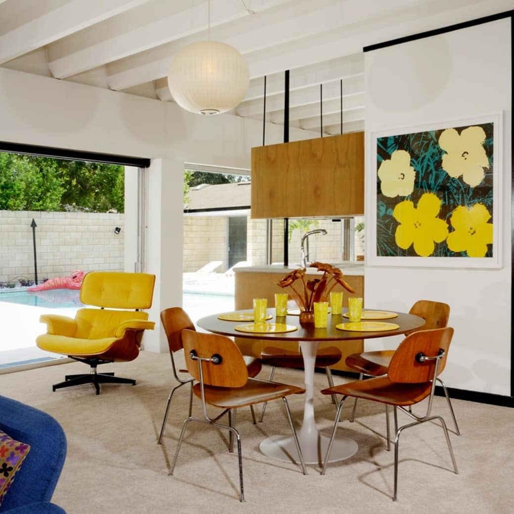 modern open kitchen dining room round wood dining table flower wall print yellow chair pool